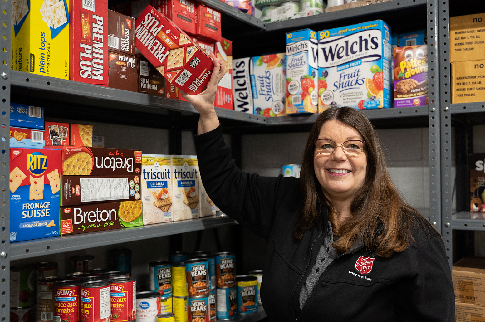 Salvation Army worker smiling in front of food bank shelves