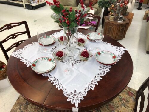 A brown round table with red and white Christmas housewares and decor
