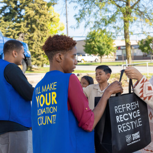 Family handing over a bag of donations to a thrift store employee