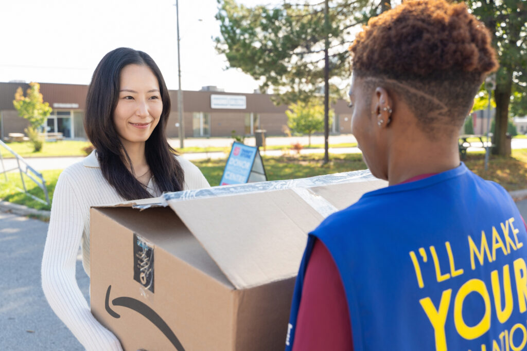 Handing over a box of donations to a thrift associate