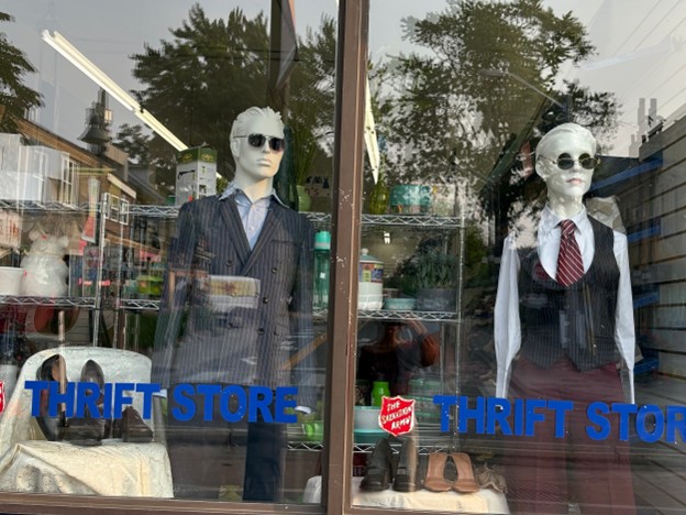 workwear outfits including blazer, dress shirt, and sunglasses on a male mannequin and a vest, tie, collar top, and sunglasses on a female mannequin from a window display