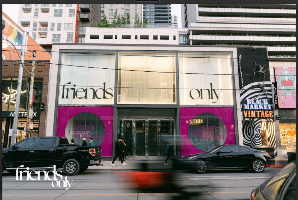 Zara storefront with window panels saying friends only. Cars passing by and people walking in front of the store