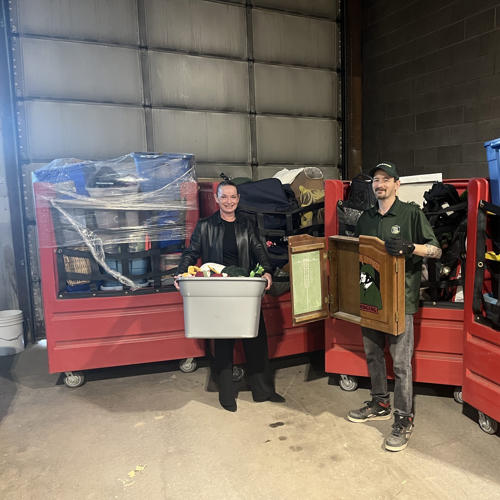 Just Junk Calgary employee standingwith Thrift Store attendant in front of bins of corporate partnership donations