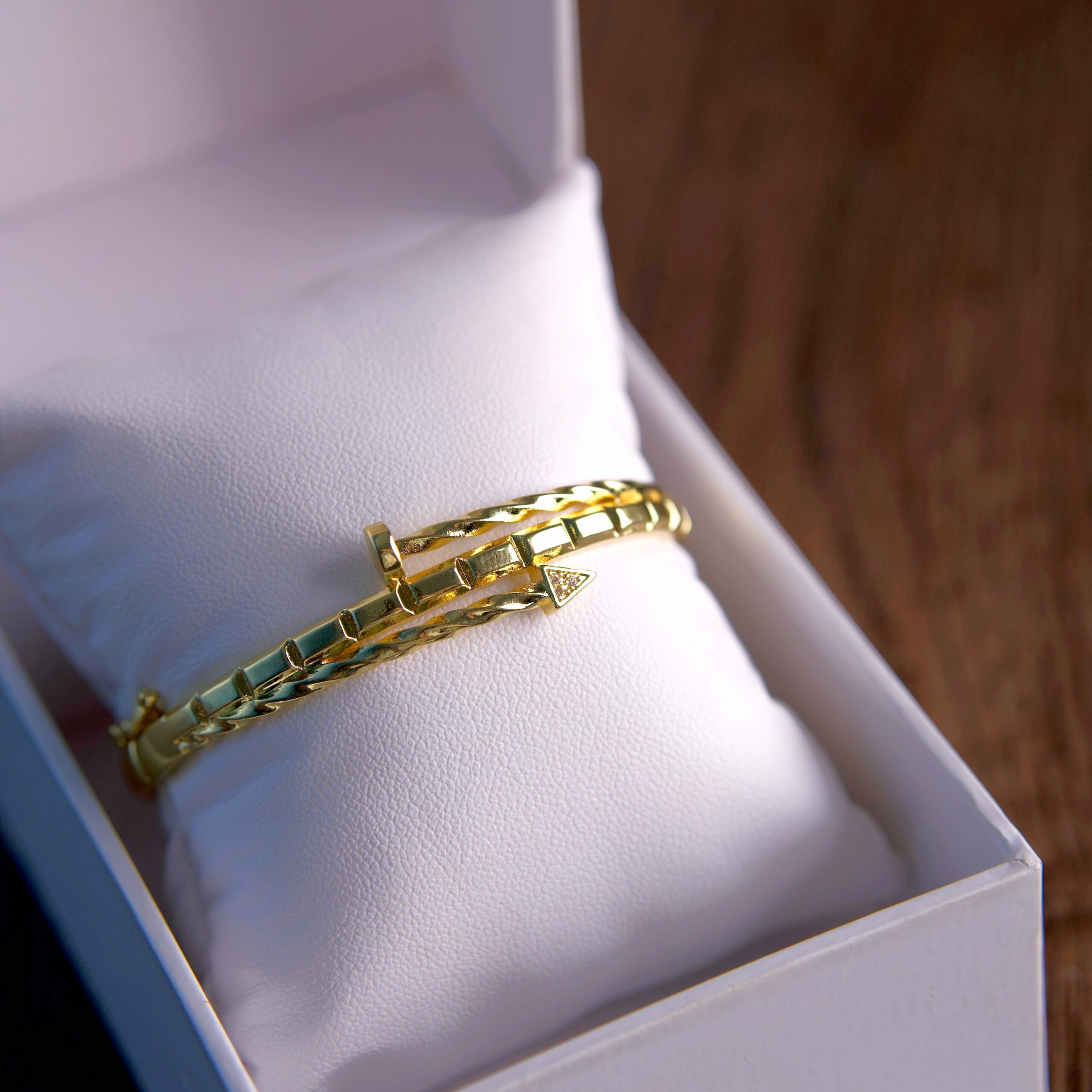 Gold bracelet around a jewelry pillow with box lid open