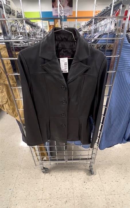 Black Women's leather jacket hanging on the end of an aisle rack