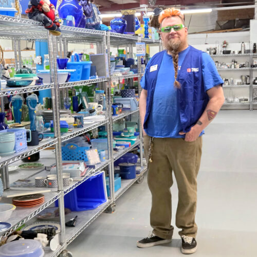 Employee Jeff standing in a Thrift Store aisle with blue housewares