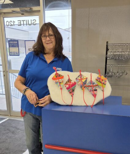 Bonnie Richards smiling beside her quilted pieces