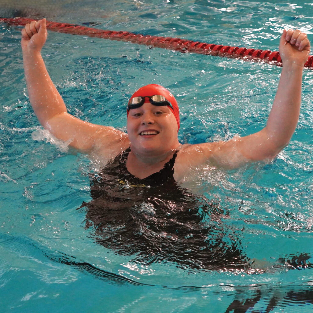 Casey cheering hands in the air in the swimming pool water