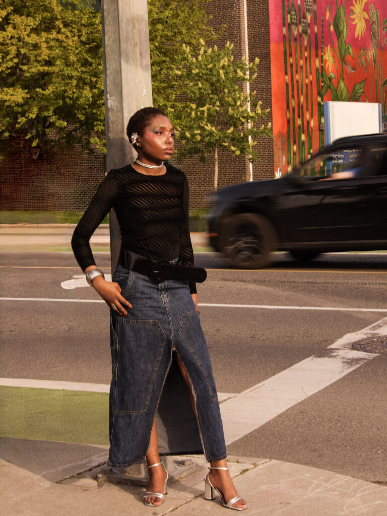 Our collaborator Kendra wearing a black sheer layered longsleeve, jean maxi skirt outside on the street