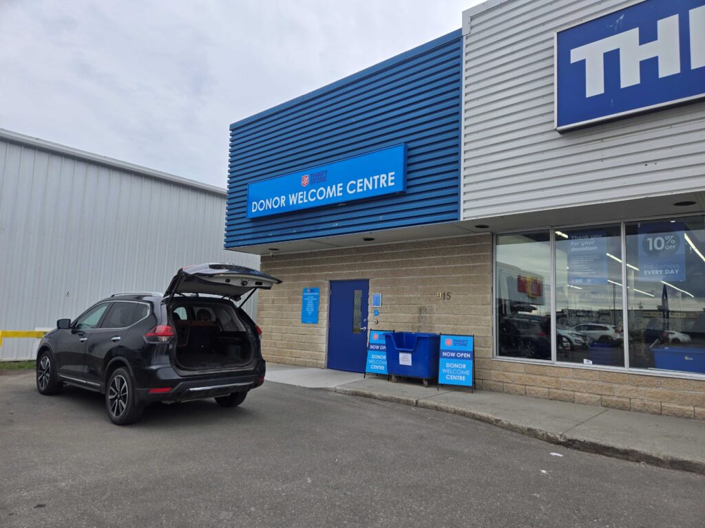 black car in front of Salvation Army donor welcome centre with trunk open